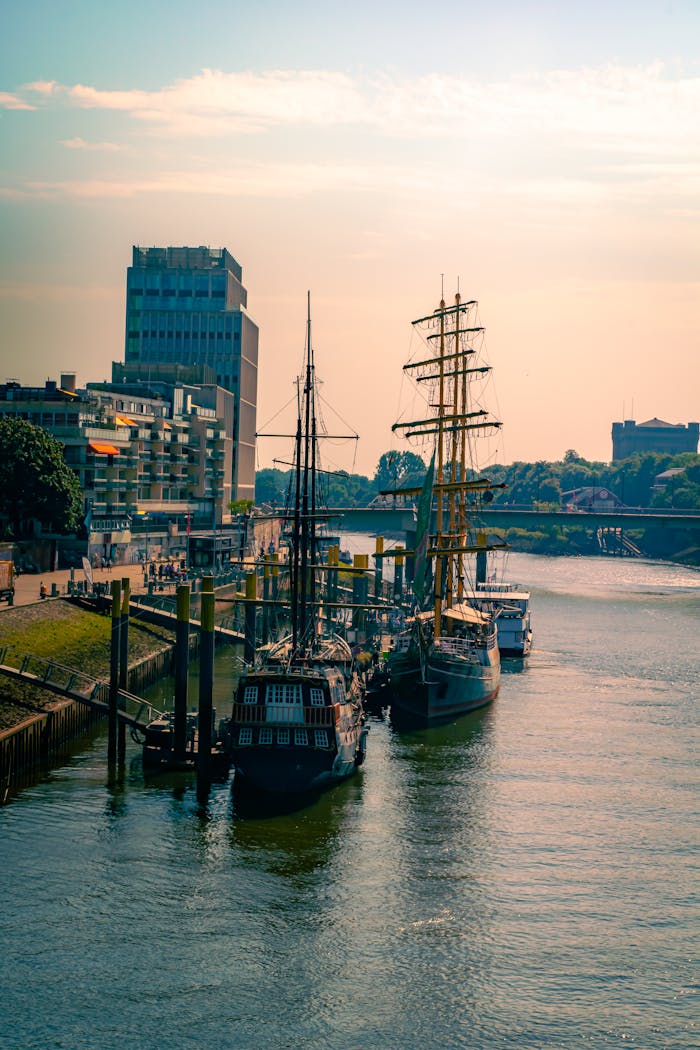 Explore the serene beauty of tall ships docked along the Weser River in Bremen at sunrise.